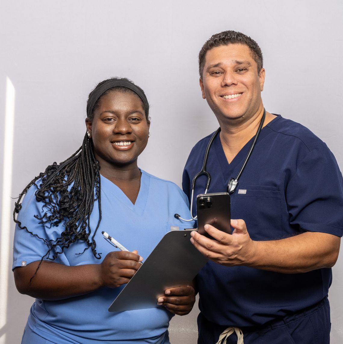two healthcare workers smiling and looking at the camera