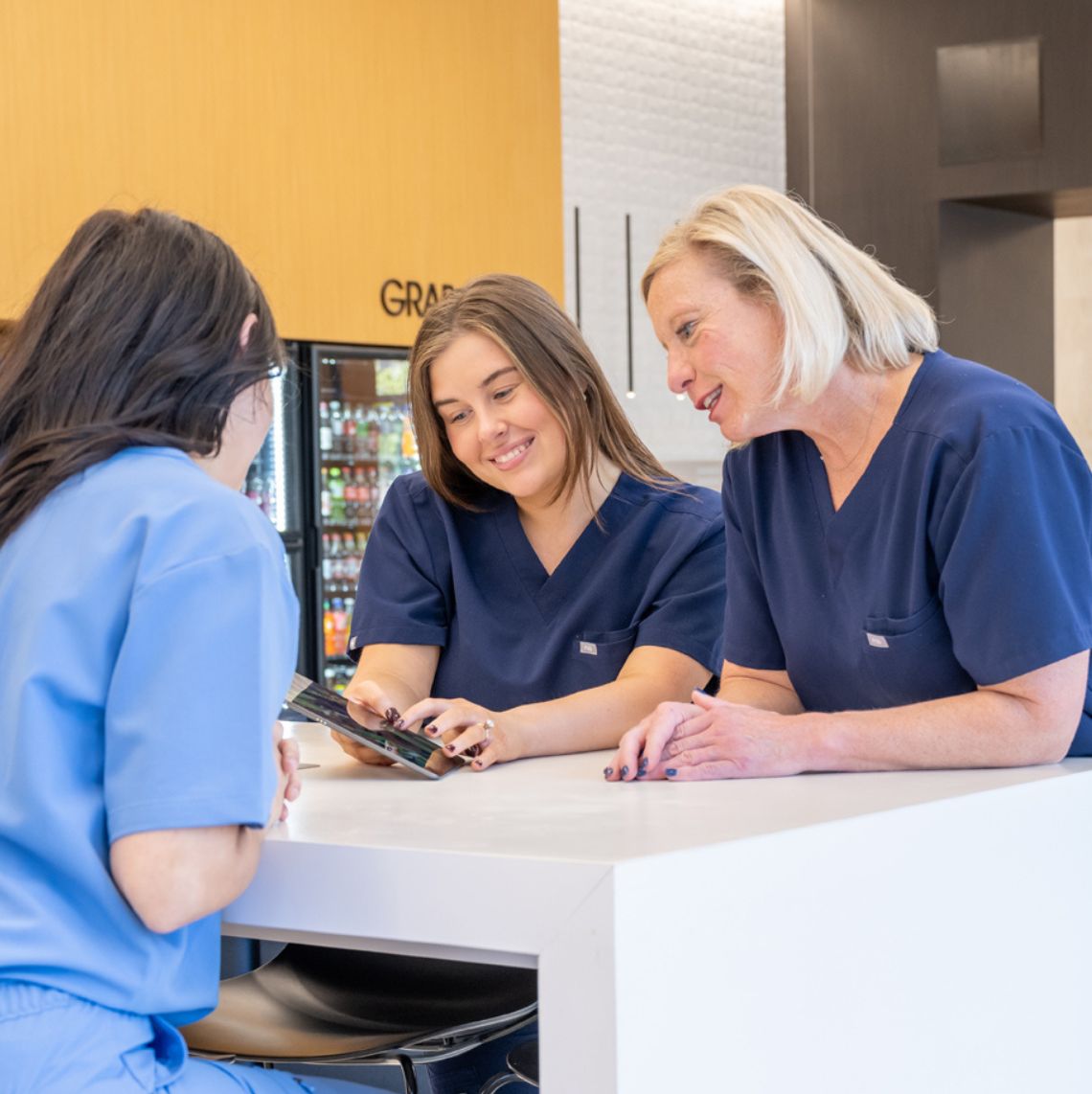 3 women in scrubs looking at a tablet